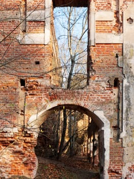 Ruins of an old ancient abandoned building. A badly damaged red brick wall.