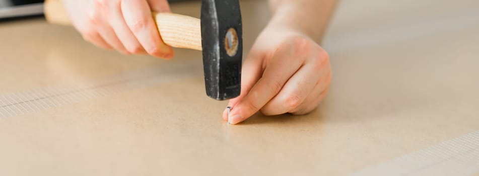 Close-up of hammering a nail into wooden board