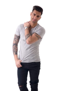 Handsome tattooed young man wearing grey t-shirt, standing isolated against white background in studio shot