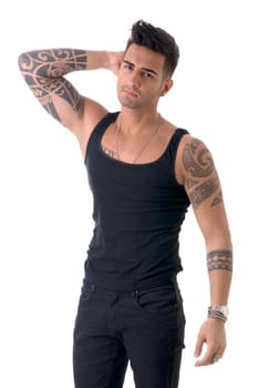 Handsome tattooed young man wearing black tank-top, standing isolated against white background in studio shot