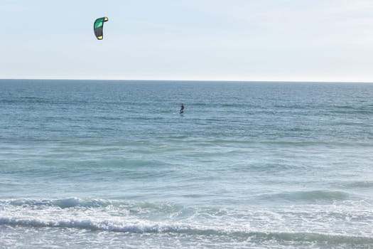 A person kitesurfing in the ocean. Mid shot