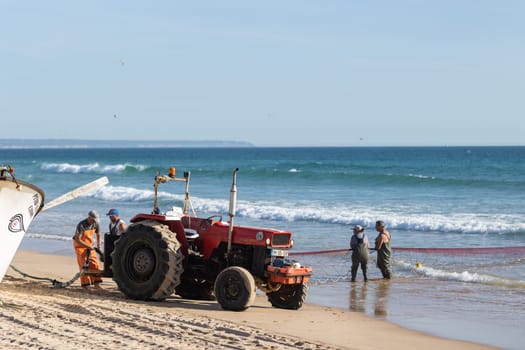 24 April 2023 Lisbon, Portugal: fishers use a tractor to fish with a net at the sea. Mid shot