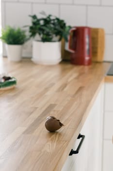 Broken chocolate egg on wooden table in kitchen - vertical photo with copy space and empty place for text concept