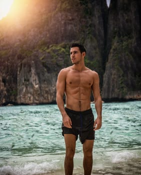 Attractive young man standing on a beach in Phuket Island, Thailand, shirtless wearing boxer shorts, showing muscular fit body