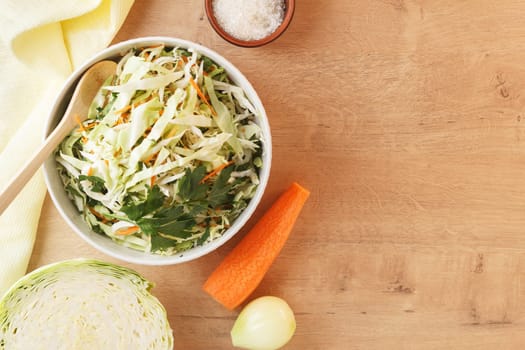 healthy vegan bowl of vegetable salad for lunch. Cabbage, carrots, parsley, onion, olive oil. Copy space