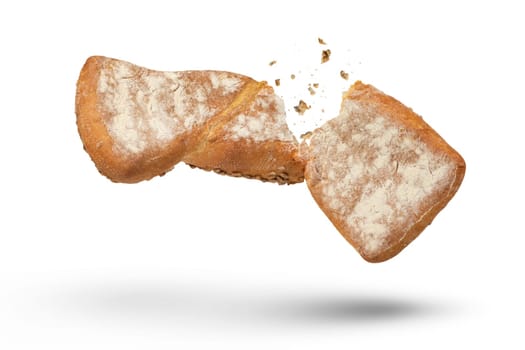Loaf of crispy bread isolated on white. A loaf of freshly baked crispy bread is broken in half with crumbs flying in all directions at the break. Fresh baking concept. Bottom view. High quality photo