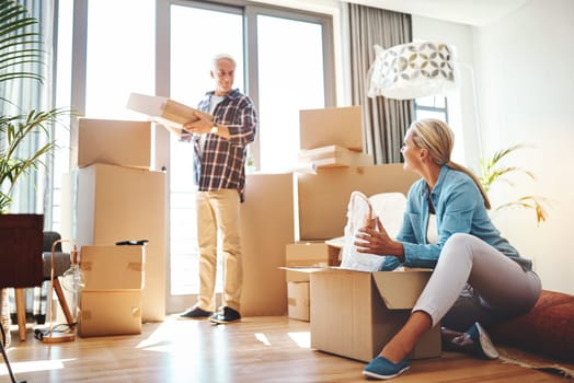 Real estate, property and a senior couple moving house while packing boxes together in their home. Box, investment and retirement with old people unpacking in the living room of their new apartment.