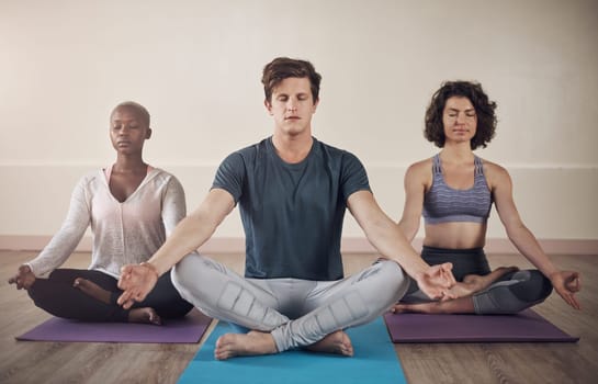Go within every day and find the inner strength. Full length shot of a diverse group of yogis sitting together and meditating after an indoor yoga session