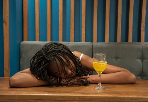 drunk girl asleep on top of a table and a glass of alcohol next to her. High quality photo