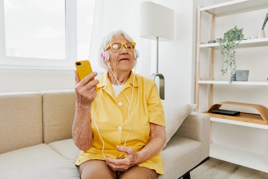 Happy elderly woman looking into phone video call smile, technology for communication, bright modern interior, lifestyle online communication. High quality photo