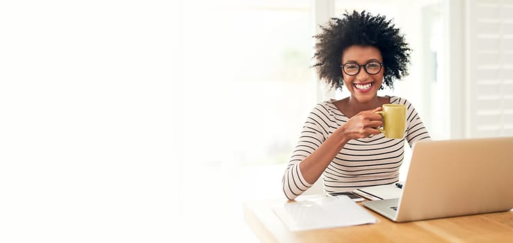 Cropped portrait of a young woman drinking coffee while working on her laptop at home.