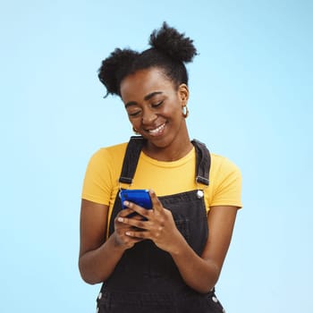 Black woman with smartphone in hands, smile and happy with chat or social media, communication isolated on blue background. Technology, happiness and gen z youth, phone with internet wifi and mockup.