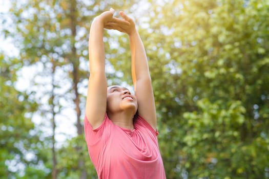 Young Asian woman in sportswear stretches before exercising in the park for a healthy lifestyle. Young healthy woman warming up outdoors. Healthy lifestyle concept.