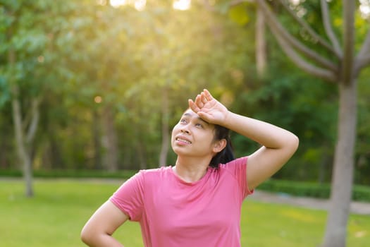 Portrait of young Asian woman in sportswear resting after jogging. Healthy young woman taking a break after jogging in the park. Healthy lifestyle concept.