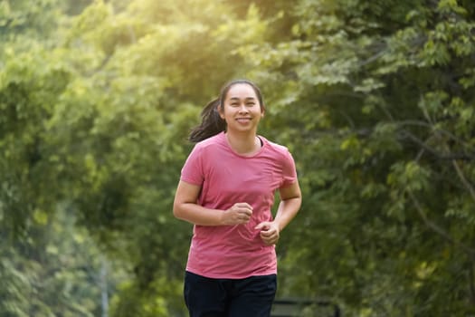 Woman jogging in the park in the sunshine on a beautiful summer day. Beautiful young woman jogging training exercise. Healthy lifestyle concept.