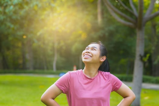 Portrait of young Asian woman in sportswear resting after jogging. Healthy young woman taking a break after jogging in the park. Healthy lifestyle concept.