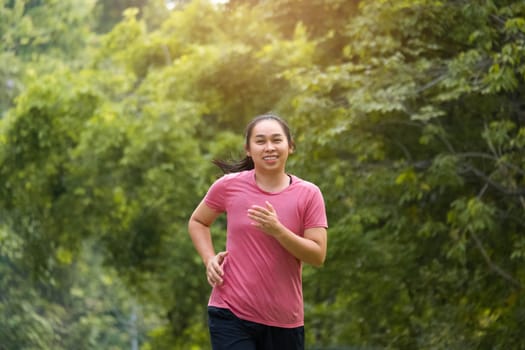 Woman jogging in the park in the sunshine on a beautiful summer day. Beautiful young woman jogging training exercise. Healthy lifestyle concept.