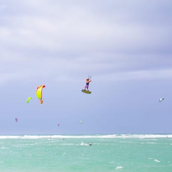 Kiteboarding. Fun in the ocean. Extreme Sport Kitesurfing. Kitesurfer jumping high in the air performing triks during kitesurfing session