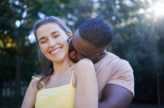 Love, park and kissing with an interracial couple bonding outdoor together on a romantic date in nature. Summer, romance and diversity with a man and woman dating outside in a green garden.
