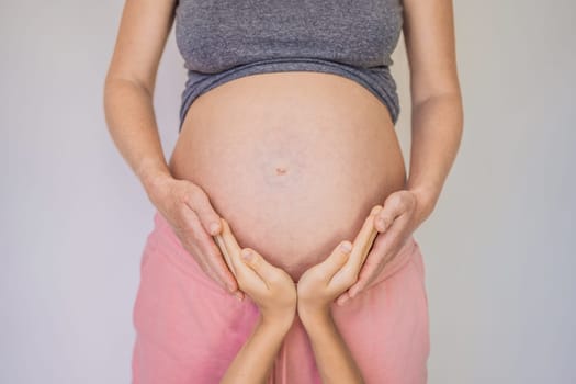 Young beautiful pregnant woman and eldest son. The cute boy put his hands on his mother's belly. Expecting a baby in the family concept. Preparing an older child for a younger one.