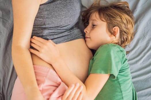 Young beautiful pregnant woman and eldest son. The cute boy leaned his ear against his mother's belly. Expecting a baby in the family concept. Preparing an older child for a younger one.