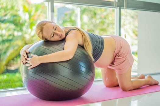 Pregnant woman exercising on fitball at home. Pregnant woman doing relax exercises with a fitness pilates ball. Against the background of the window.