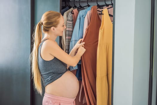 A pregnant woman has nothing to wear. A pregnant woman stands in front of a closet with clothes and does not know what to wear because the clothes do not fit on her.