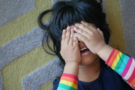a upset child girl cover her face with hand .