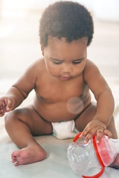 Children, black baby and girl with a bottle sitting on a blanket on the floor of a home for child development. Kids, cute and curious with a newborn infant learning or growing alone in a house.