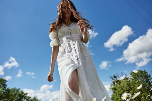 a woman in a light dress against a blue sky with hair covering her face. Photo from below. High quality photo