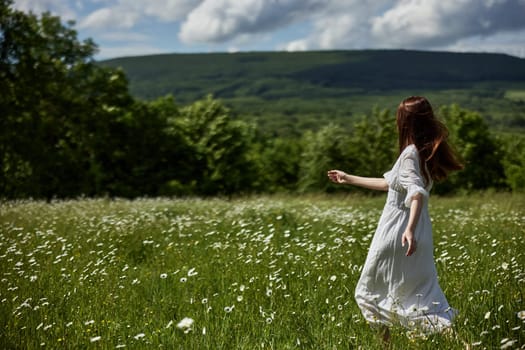 a free woman in a light dress runs through a field of daisies with her back to the camera. High quality photo