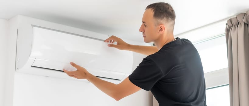 Rear View Of A Man Cleaning Air Conditioning System.