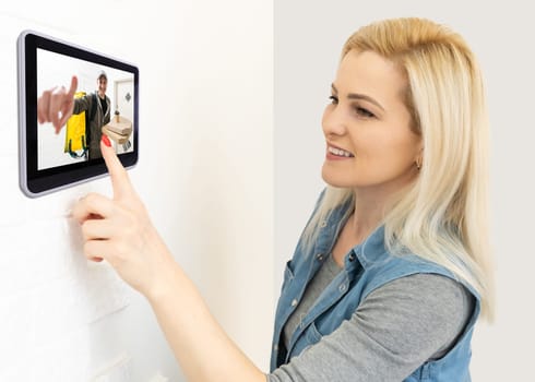 Woman watching delivery man on security camera cctv video on tablet.