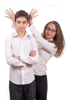 Portrait of cute schoolchildren. A girl and a guy in school clothes are having fun and joking, playing tricks on each other. The girl shows the horns.