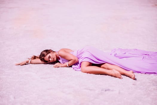 A woman in a pink dress lies on the shore of a pink lake, takes a photo for memory and leaves unforgettable memories