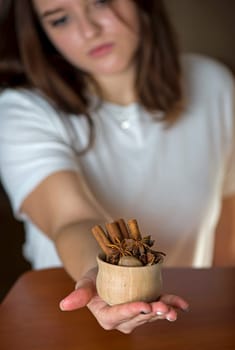 A girl shows a cup with spices for mulled wine