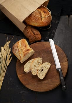 Fresh bread on table close-up. Fresh bread on the kitchen table Whole grain bread put on kitchen wood plate with a knife for cut. Freshly baked rye bread on a wooden board.