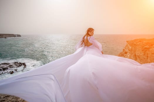 Woman sea white dress. Happy freedom woman on the beach enjoying and posing in white dress. Rear view of a girl in a fluttering white dress in the wind. Holidays, holidays at sea