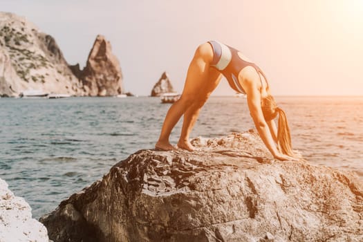 Yoga on the beach. A happy woman meditating in a yoga pose on the beach, surrounded by the ocean and rock mountains, promoting a healthy lifestyle outdoors in nature, and inspiring fitness concept