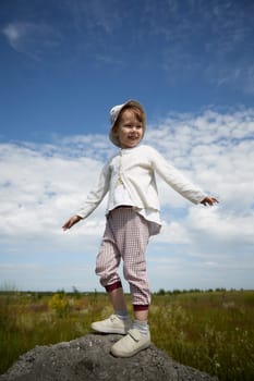 Portrait of little girl with Asian eyes in a meadow or field with grass and flowers on a sunny summer day