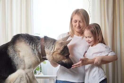 Happy loving family with mother, daughter and big dog in living room. Pet chephers, woman mom and small child girl who is afraid of a dog taken from a shelter