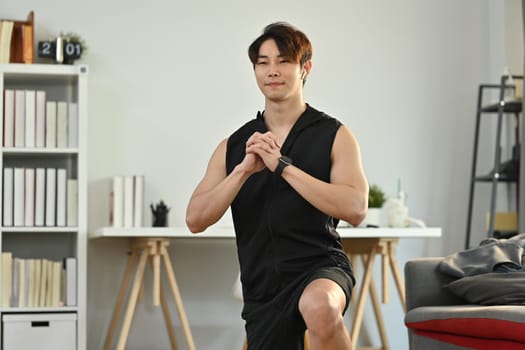 Handsome male athlete in fitness clothes working out in the morning at home. Healthy lifestyle concept.