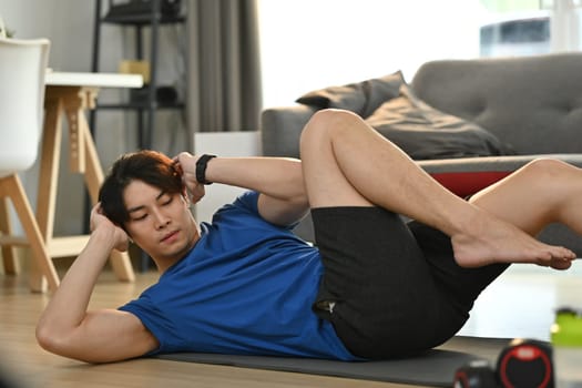 Shot of sportive asian man doing sit ups Abs exercise at home. Healthy lifestyle and sport concept.