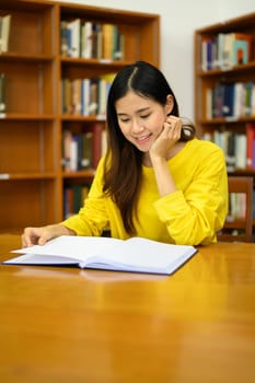 Serene female student reading book in a library for studying and research. Education, learning, knowledge and university.