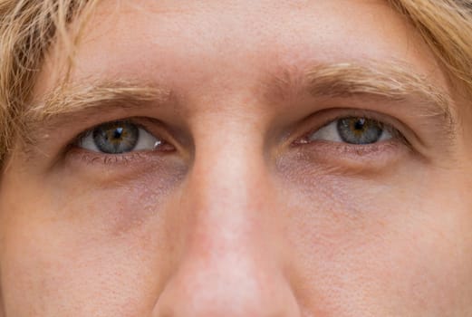 Extreme close-up macro portrait of face. Young adult beautiful redhead man's eyes looking at camera. Gray eyes of guy, red hair boy male. Caucasian man opening blinking eyes, smiling. Laser correction