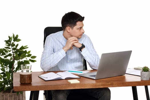 sad businessman using laptop, sitting on chair at desk, having problems thinking about troubles in office