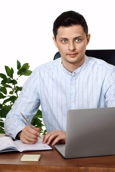 businessman in blue shirt taking notes, using laptop computer on white background