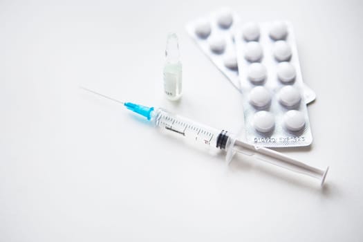Preparation for vaccination against covid-19. Syringe, vaccine, pills, medical mask on a white table