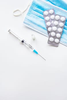 Preparation for vaccination against covid-19. Thermometer, pills, medical mask on a white table. Place for an inscription, vertical photo