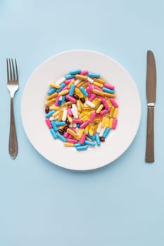 Tablets, capsules, vitamins and natural organic food supplements on a white plate on a blue background. Minimal modern pharmacy or healthcare concept. Vertical photo